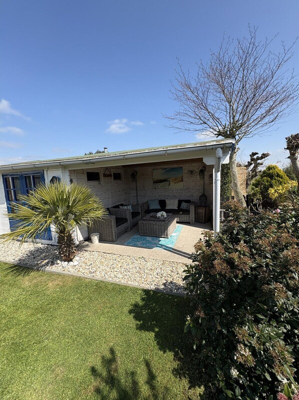 A house with a covered patio, outdoor furniture, and a small palm tree.