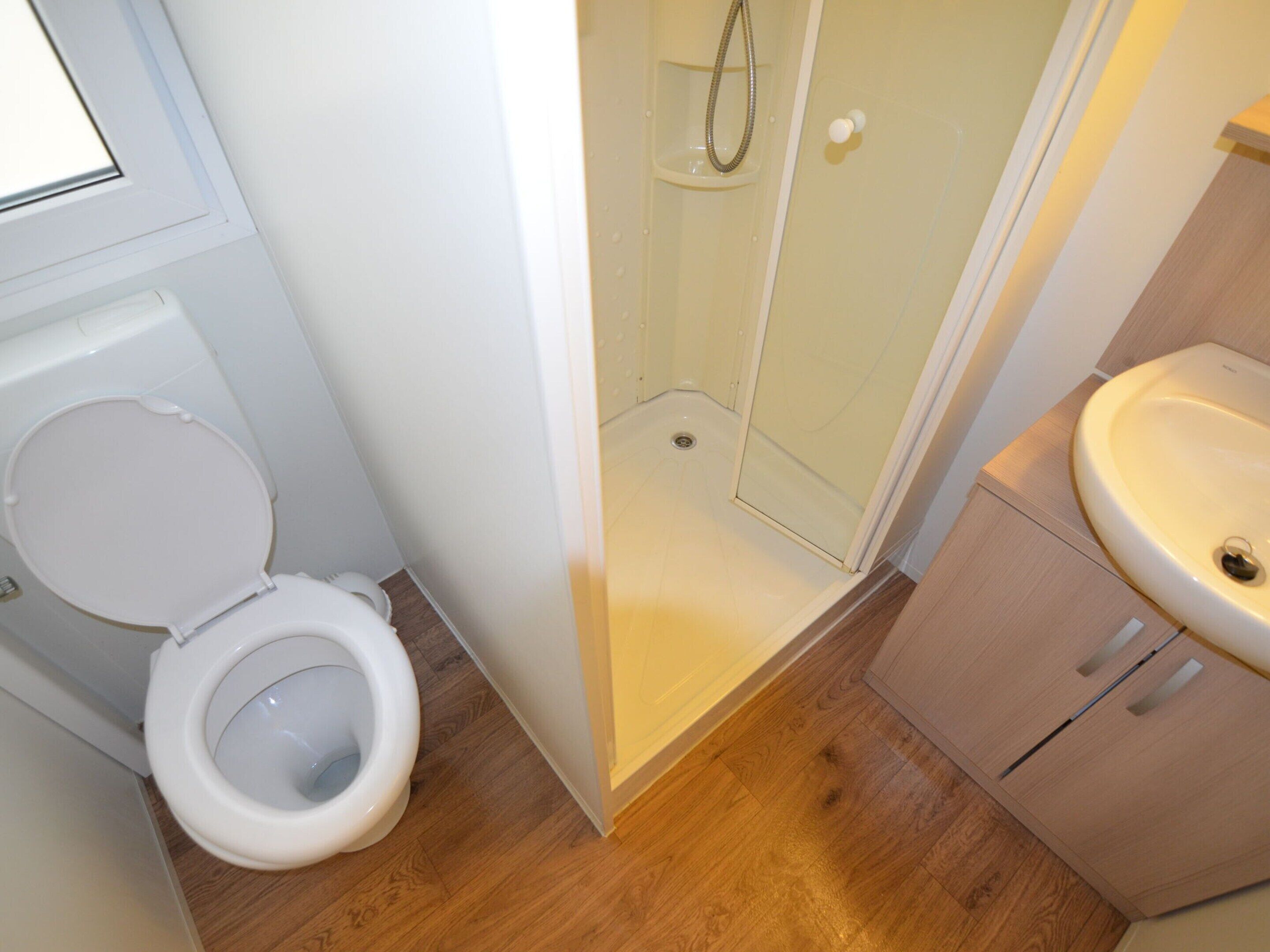 A bathroom with a toilet, a shower enclosure, and a sink.