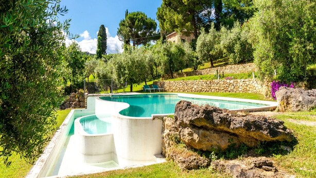 A swimming pool with a stone wall and a grassy area with trees. - Rustic Villa with Private Pool near Montepulciano (Montepulciano)