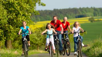 A family riding bicycles on a paved path surrounded by greenery.