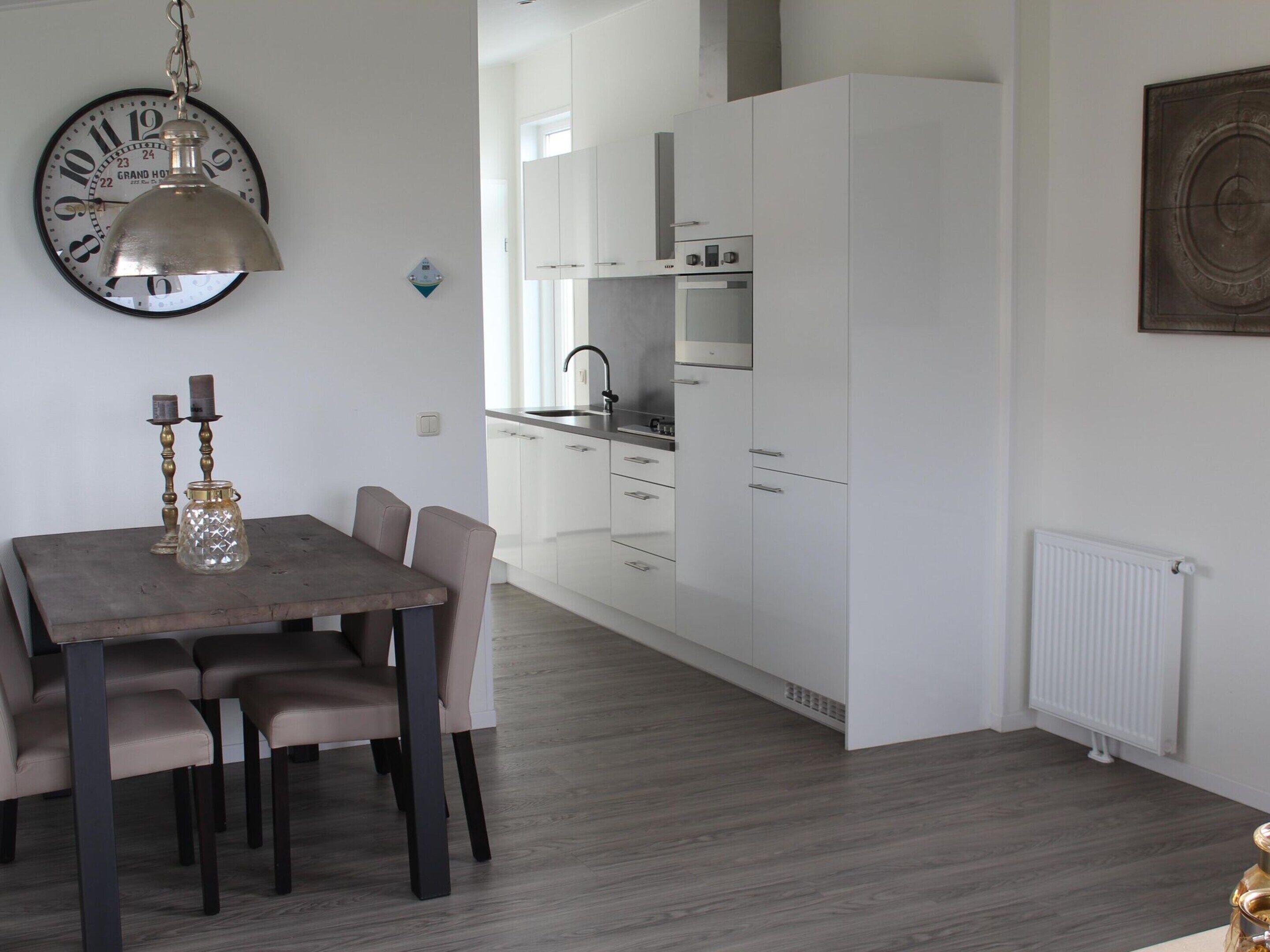 A modern kitchen with white cabinets, a built-in oven, and a stainless steel sink.
