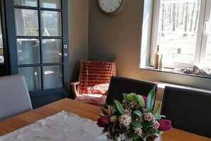 A dining area with a table, chairs, a clock on the wall, and a window with a view.