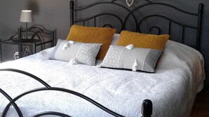 A bed with a metal frame, a bedside table, a lamp, and a decorative heart on the wall. - Sunny Garden Cottage, Alle (Vresse-sur-Semois)