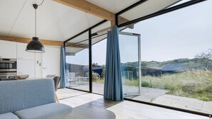 Ein modernes Wohnzimmer mit einer Couch, einem runden Tisch und einer großen Schiebeglastür, die auf eine Terrassenanlage hinausführt.
