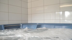 Et spabad med gelænder, omgivet af hvide flisevægge.
