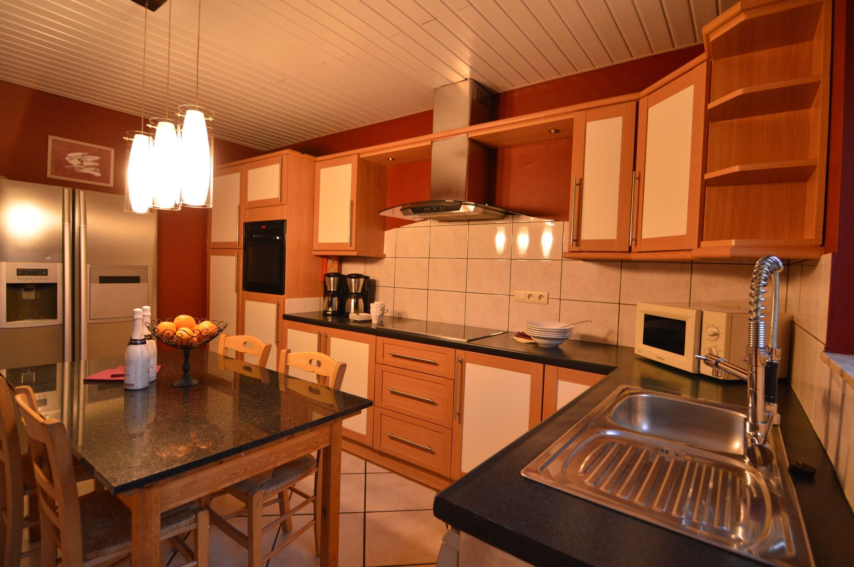 A kitchen with wooden cabinets, a stainless steel sink, a microwave, and a coffee maker.