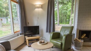 Een moderne woonkamer met een leren bank, een groene fauteuil, een houten salontafel en een flatscreen televisie.