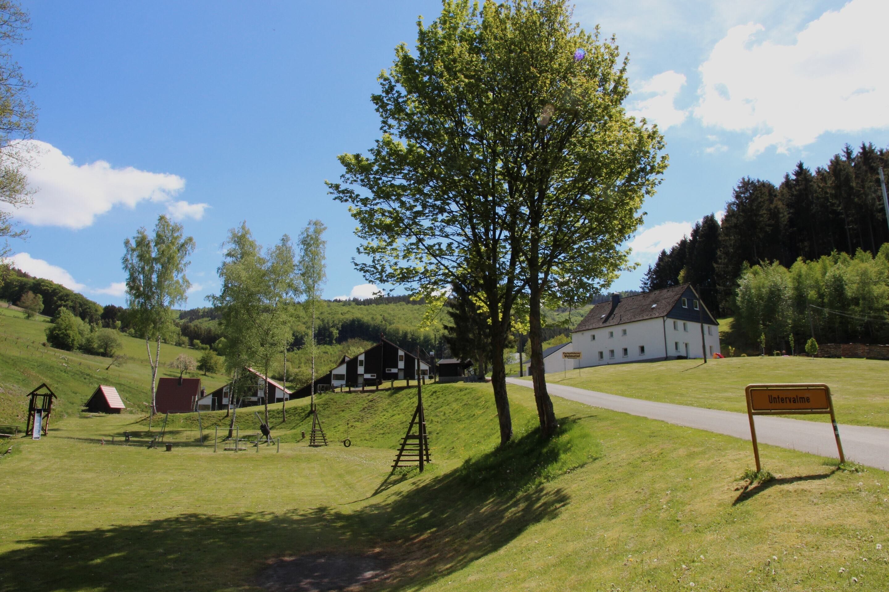 Un paysage rural avec un grand bâtiment blanc, une enseigne indiquant « Intervale », et une aire de jeux avec des balançoires et un toboggan.