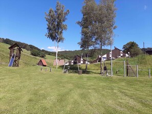 A rural setting with a wooden play structure, a small red-roofed building, and several modern houses with white walls and brown roofs. - Geraeumiges Apartment mit Privater Terrasse (Bestwig)
