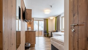 A modern hotel room with wooden flooring, a kitchenette, a dining area, and a bed. - Chalet in Saalbach Near Ski Lift and Sauna (Saalbach-Hinterglemm)