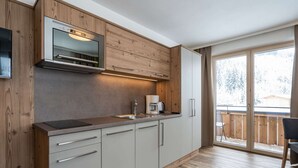 A modern kitchen with wooden cabinetry, a built-in oven, and a coffee maker. - Chalet in Saalbach Near Ski Lift and Sauna (Saalbach-Hinterglemm)