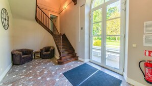 A staircase leading to an upper floor, a fire extinguisher, and a large glass door with a view of the outdoors. - Luxurious Mettet Mansion (Mettet)