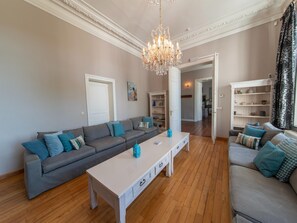 A living room with a grey sofa, a white coffee table, and a chandelier.