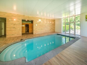 Ein Schwimmbecken mit Holzwänden und Blick auf grüne Vegetation.