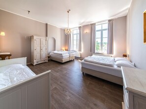 Un dormitorio amplio con dos camas, un armario y ventanas grandes.