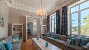 A spacious living room with a chandelier, sofas, a coffee table, and large windows with curtains. - Luxurious Mettet Mansion (Mettet)