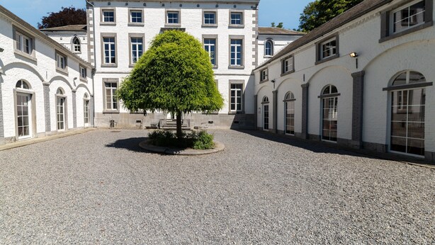 A courtyard with a central tree, surrounded by white buildings with arched windows and a symmetrical design. - Luxurious Mettet Mansion (Mettet)