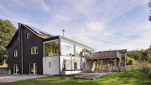 A modern two-story house with a large glass window and a wooden deck. - Comfortable Chalet With Indoor Pool, Hammam and Sauna Near Stoumont (Stoumont)
