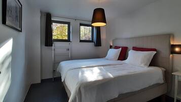 A bedroom with a bed, a window, a ladder, and a nightstand.