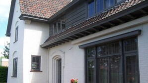 Un bâtiment blanc avec un toit en tuiles, de grandes fenêtres et une table de pique-nique en bois décorée de fleurs.