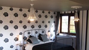 Une chambre à coucher avec un lit, un radiateur, une fenêtre avec des rideaux et un papier peint à motifs.