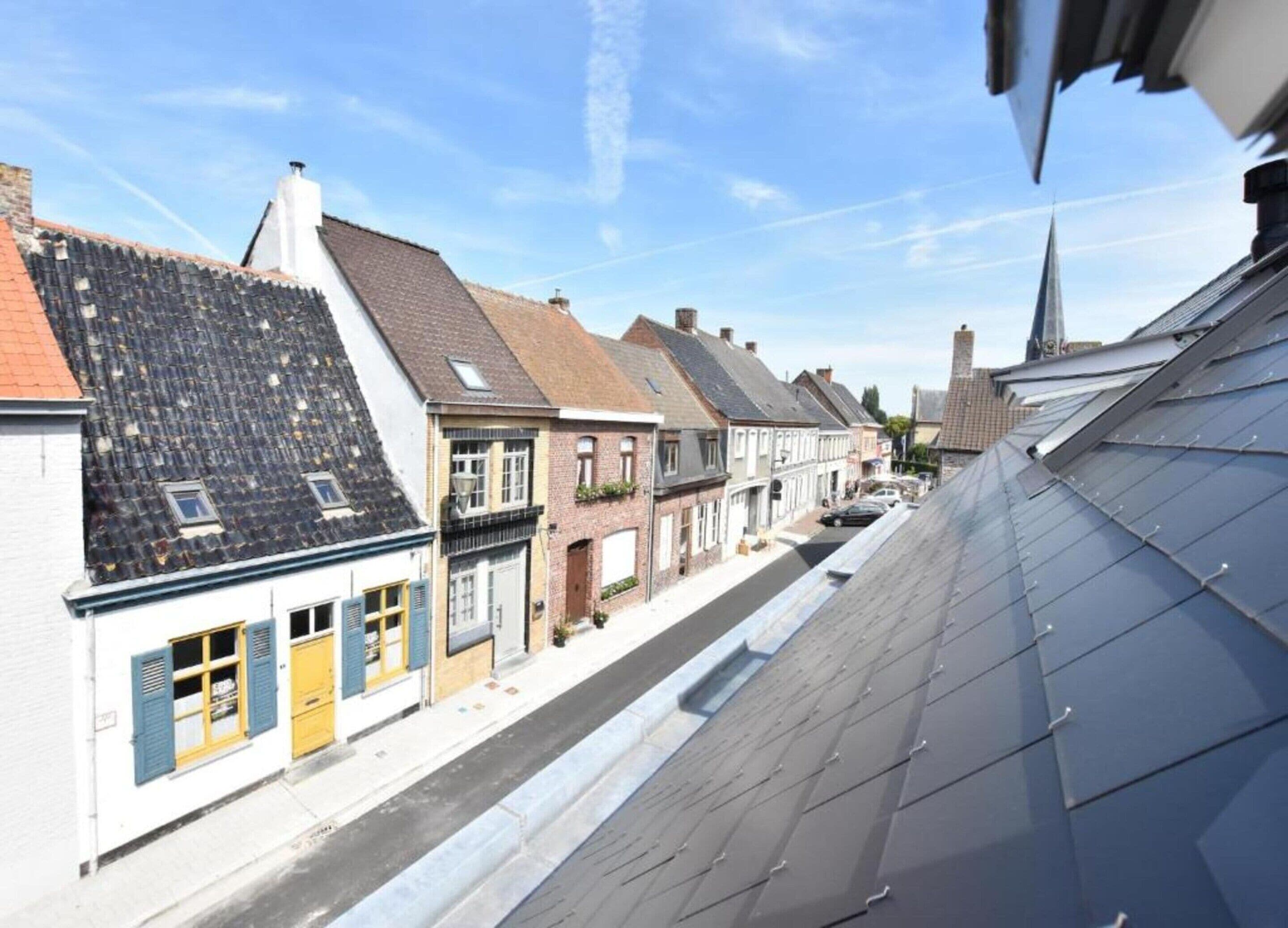 Blick auf eine Straße mit traditioneller europäischer Architektur, darunter Satteldächer und Backsteinfassaden.