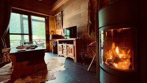Une pièce confortable avec une cheminée, un téléviseur et une vue sur l’extérieur.