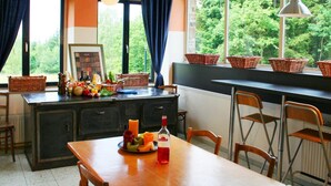 A kitchen with a wooden table, chairs, a clock, and a window with baskets. - Beautiful Country House in the Ardennes With Lots of Privacy (La Roche-en-Ardenne)