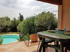 An outdoor patio with a pool, a table with chairs, and a view of the surrounding greenery. - New Villa, Round Swimmingpool, Beautiful View (Saint-Laurent-de-Carnols)