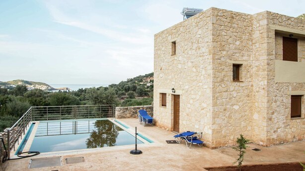 Edifici de pedra amb una piscina, un petit jardí i vistes al mar.