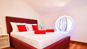 A modern hotel room with a large bed, a round window, and wooden flooring. - Villa in Murter Near Kornati National Park (Murter-Kornati)