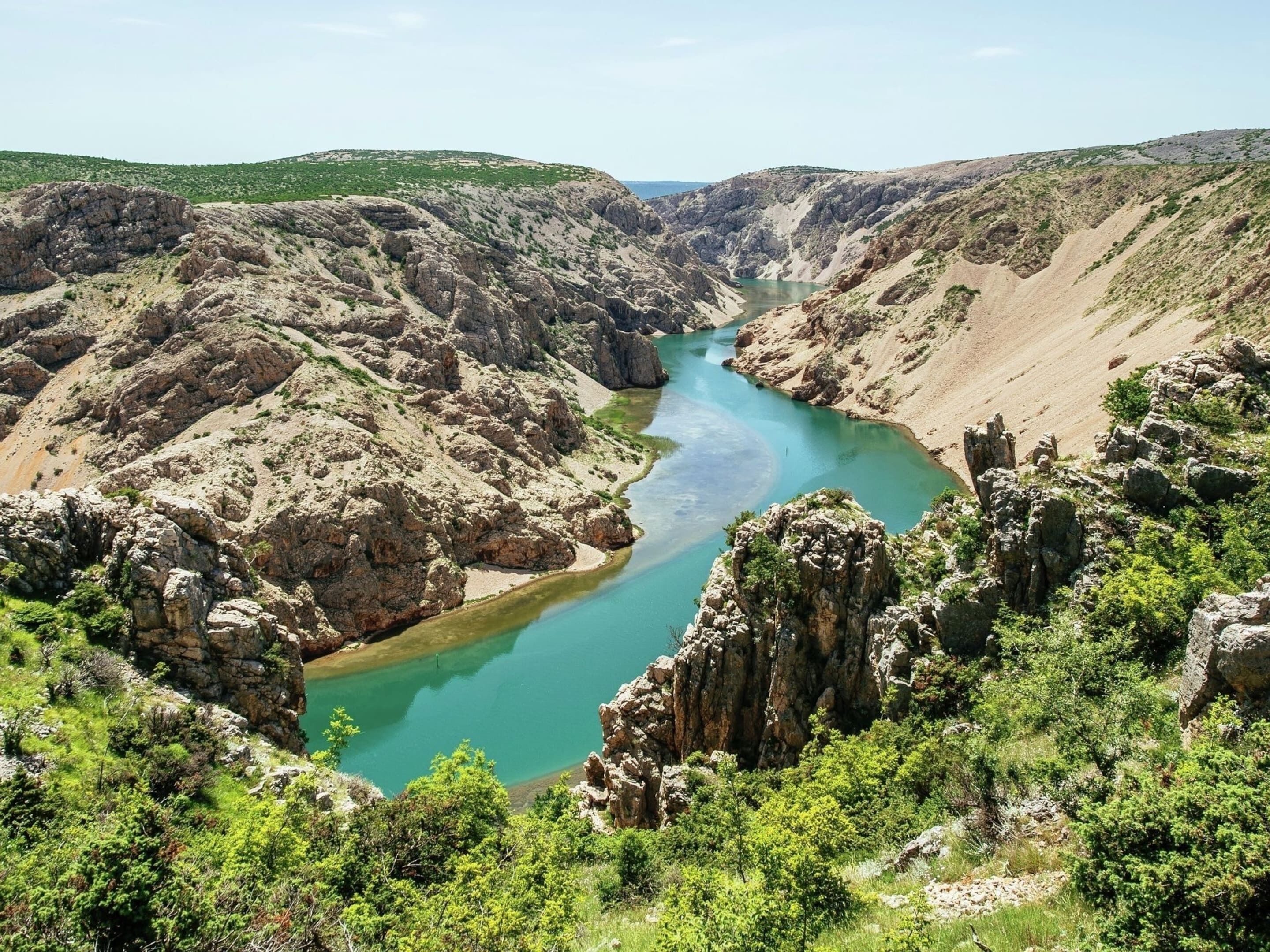 Un cañón con un río, terreno rocoso y vegetación escasa.