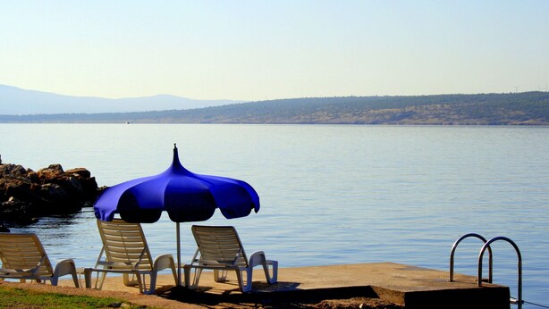 A beach with lounge chairs and a blue umbrella. - Apartment in Maslenica Near the Sea (Jasenice)