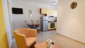 A compact living space with a dining area, a kitchenette, and a seating area with a table and a chair. - Apartment in Maslenica Near the Sea (Jasenice)