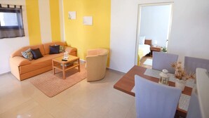 A modern living room with a sofa, armchair, coffee table, and a dining area with chairs and a table. - Apartment in Maslenica Near the Sea (Jasenice)