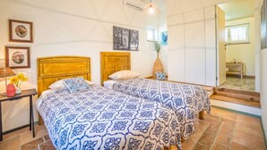 Ein Schlafzimmer mit zwei Betten, einem Nachttisch, einer Lampe und einer Vase mit Blumen.