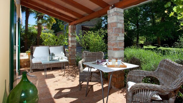 Eine Terrasse im Freien mit Korbmöbeln, einer Ziegelstütze und einem Tisch mit Tablett.