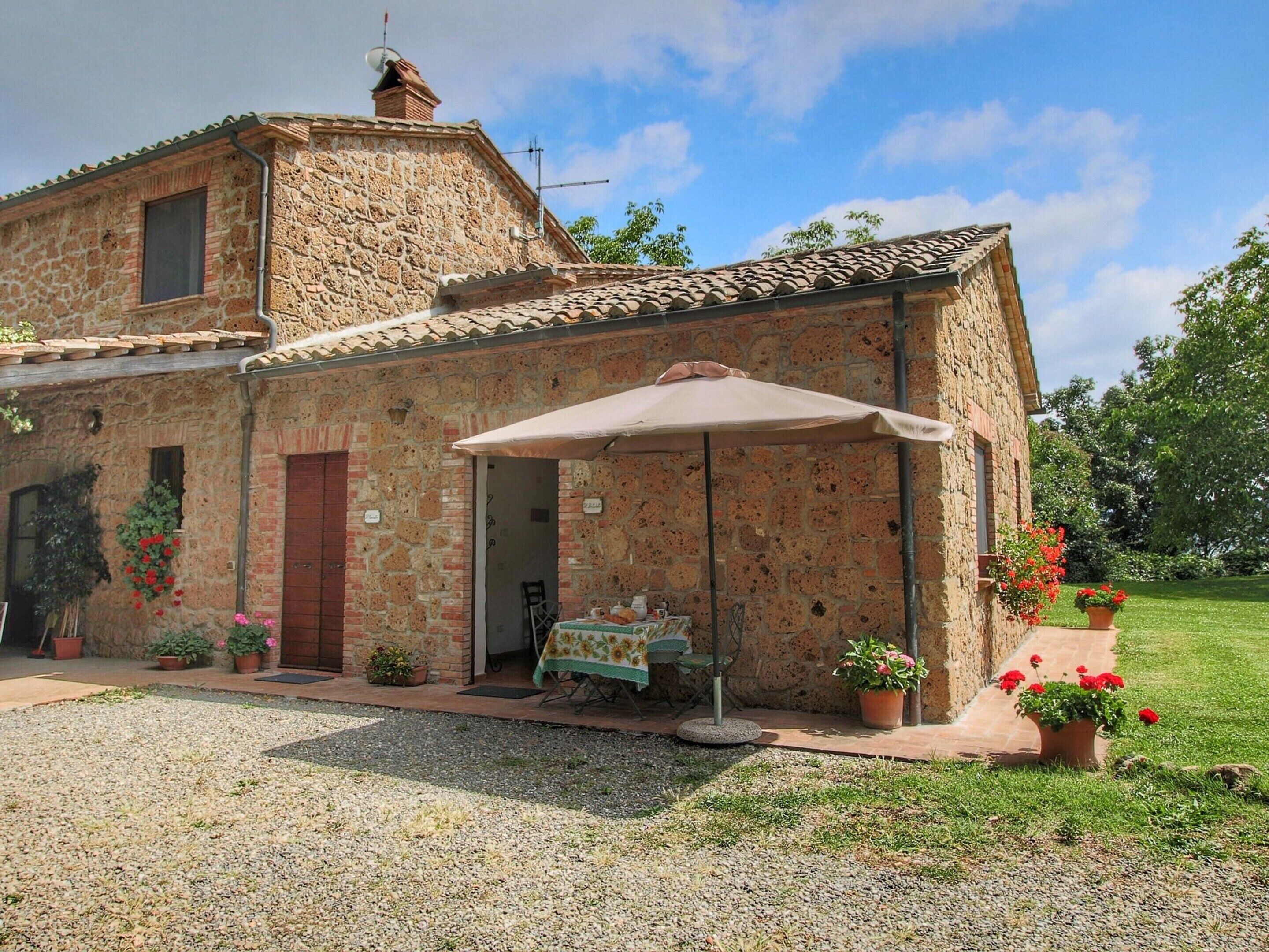 A stone building with a tiled roof, a covered outdoor seating area, and potted plants.