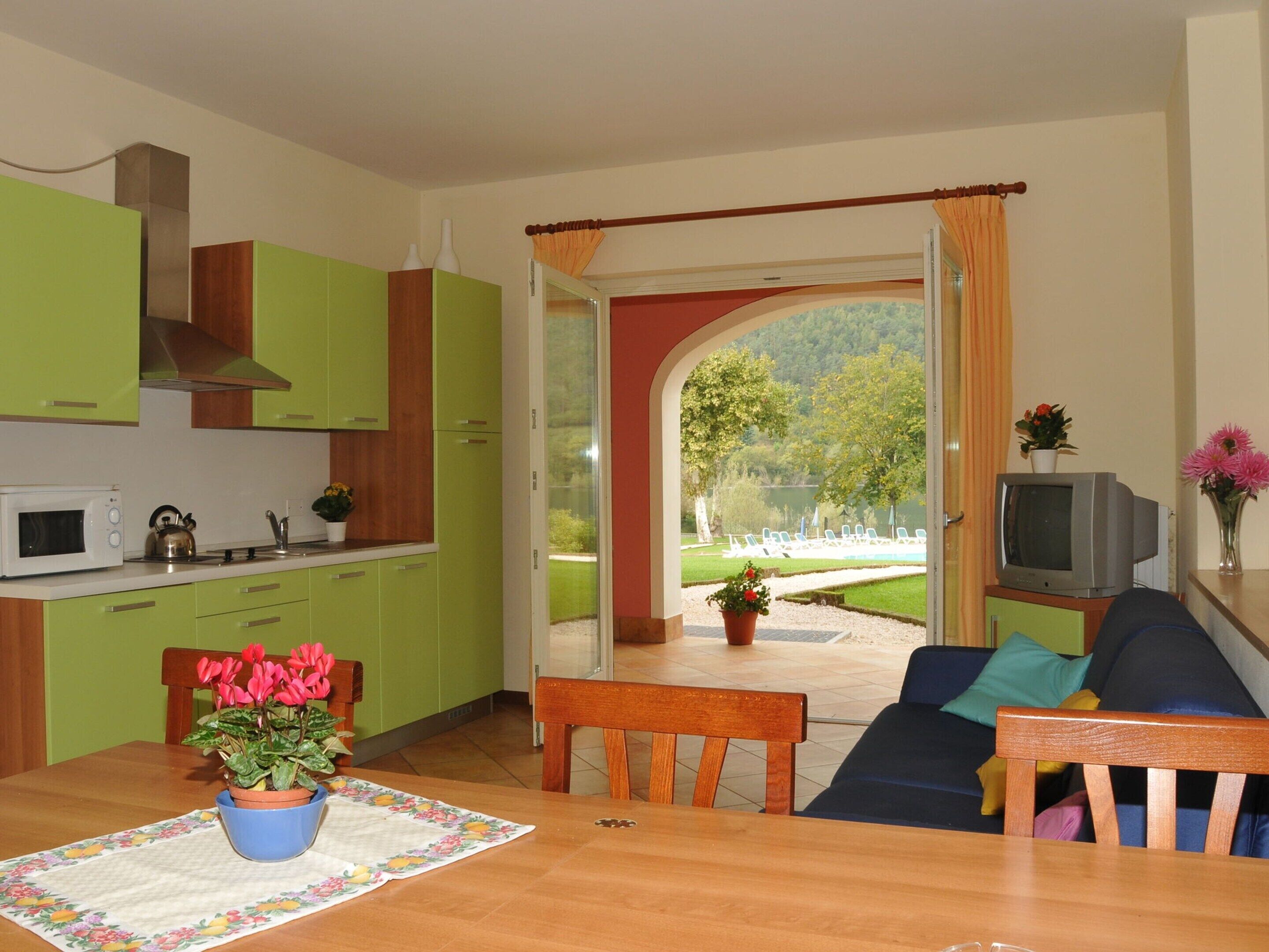 A compact living space with a kitchen, dining area, and a view of a lake.