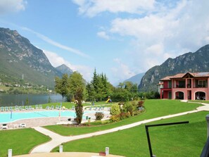 Een hotel met een zwembad, weelderige begroeiing en bergen op de achtergrond.