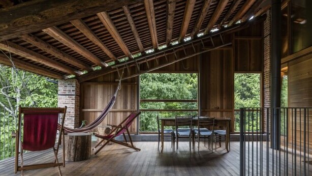 Un ponteggio in legno con un'amaca, un tavolo e delle sedie.