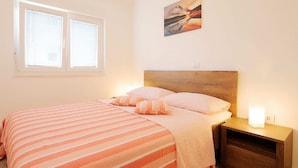 A bedroom with a bed, a nightstand, a lamp, and a window with blinds. - Apartment in Silo With Sea View Balcony (Dobrinj)