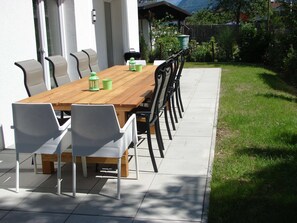 An outdoor dining area with a wooden table and chairs, a green lantern, and a trash bin. - Apartment in Zell am See Near the ski Area (Zell am See)