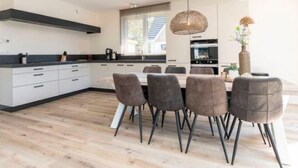 Uma cozinha moderna com armários brancos, bancada preta e um espaço de refeições com mesa e cadeiras.
