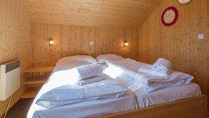 A wooden cabin room with two beds, a heater, and wall-mounted lights. - Luxury Retreat With Relaxing Bubble Bath (Hohentauern)