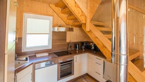 A modern kitchen with wooden accents, a built-in oven, a sink, and a stainless steel stove. - Luxury Retreat With Relaxing Bubble Bath (Hohentauern)