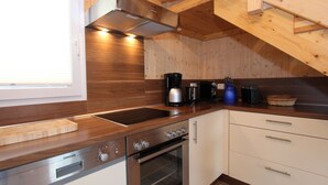 A compact kitchen with wooden cabinetry, a built-in oven, a coffee maker, and a toaster. - Luxury Retreat With Relaxing Bubble Bath (Hohentauern)