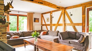 Een woonkamer met een houten tafel, twee banken, een televisie en een decoratie van een hertenkop.