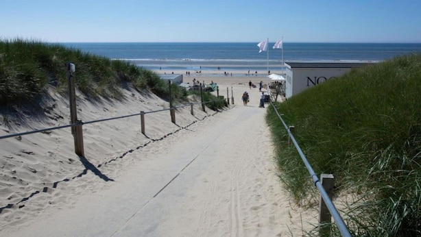A sandy beach path leading to a beach area with flags and a building labeled "NOO". - Holiday Home in Schoorl Near Forest & Beach (Schoorl)