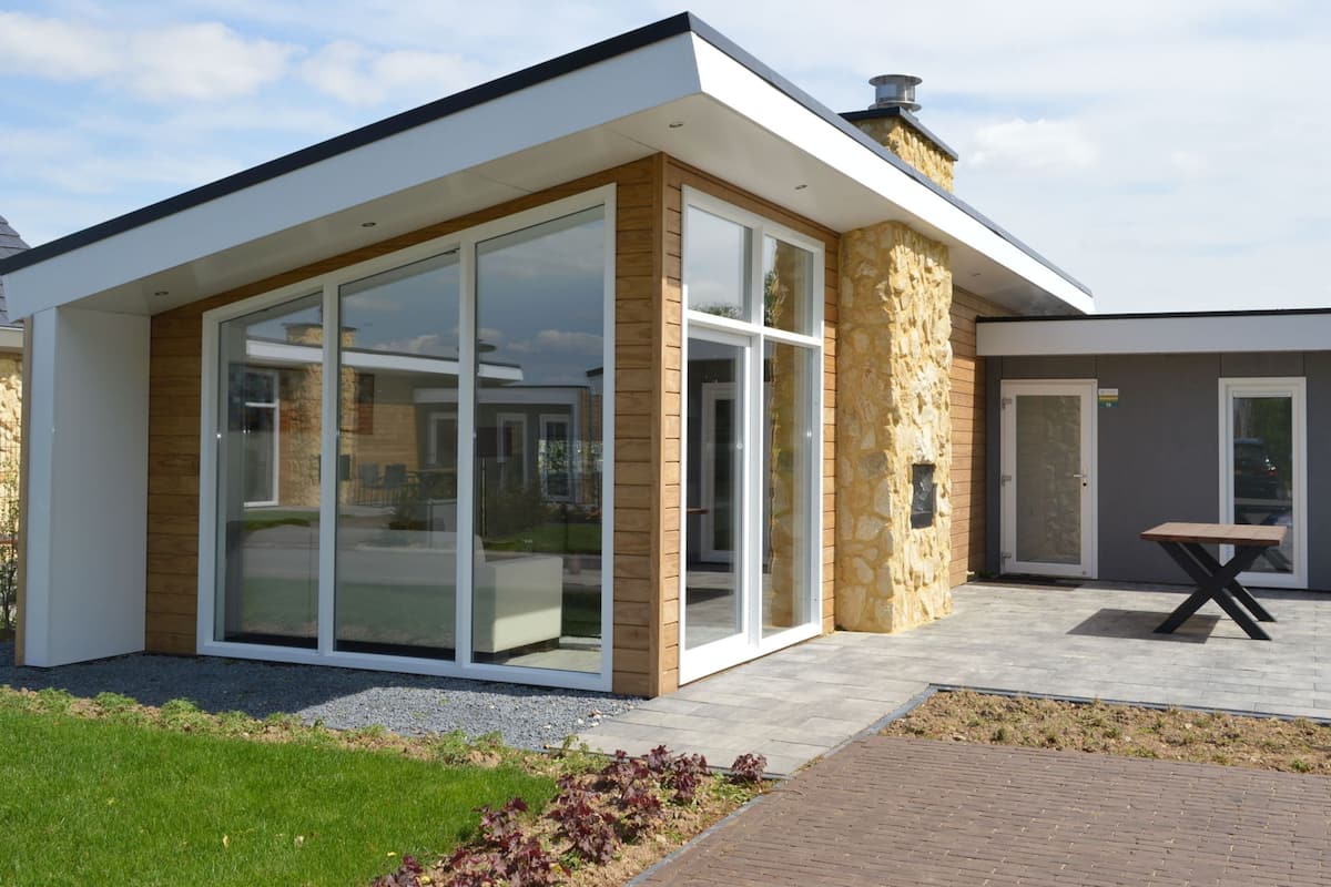 A modern house with large glass doors, a stone exterior, and a paved patio.